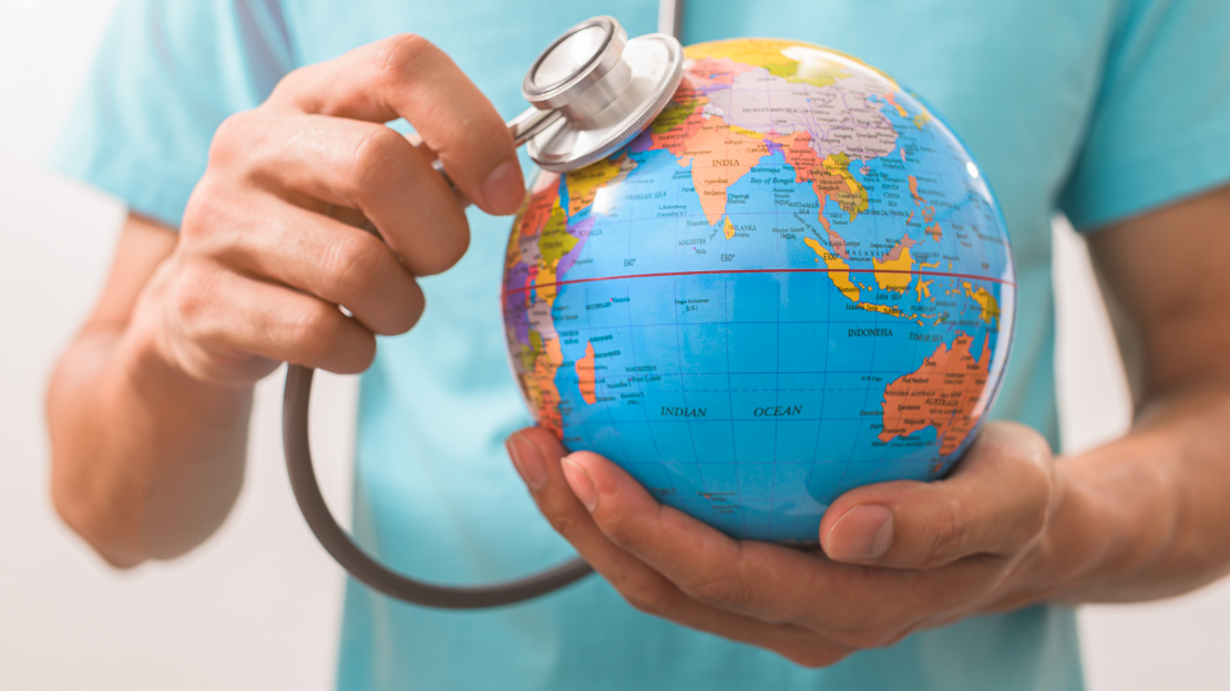 A person holding a stethoscope to a small globe