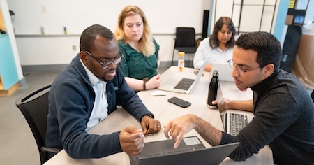 students working and pointing to a laptop