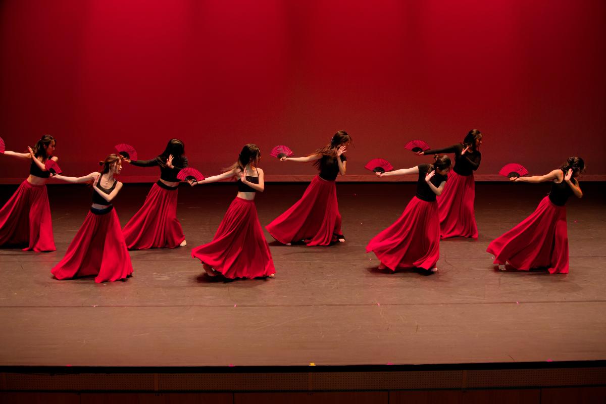 dancers with fans in red skirts on a stage