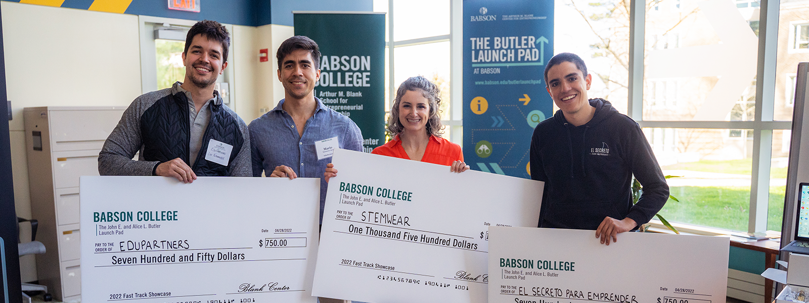 Three students holding oversized checks