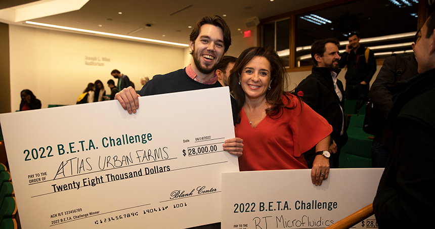 Woman and Man holding checks for competition