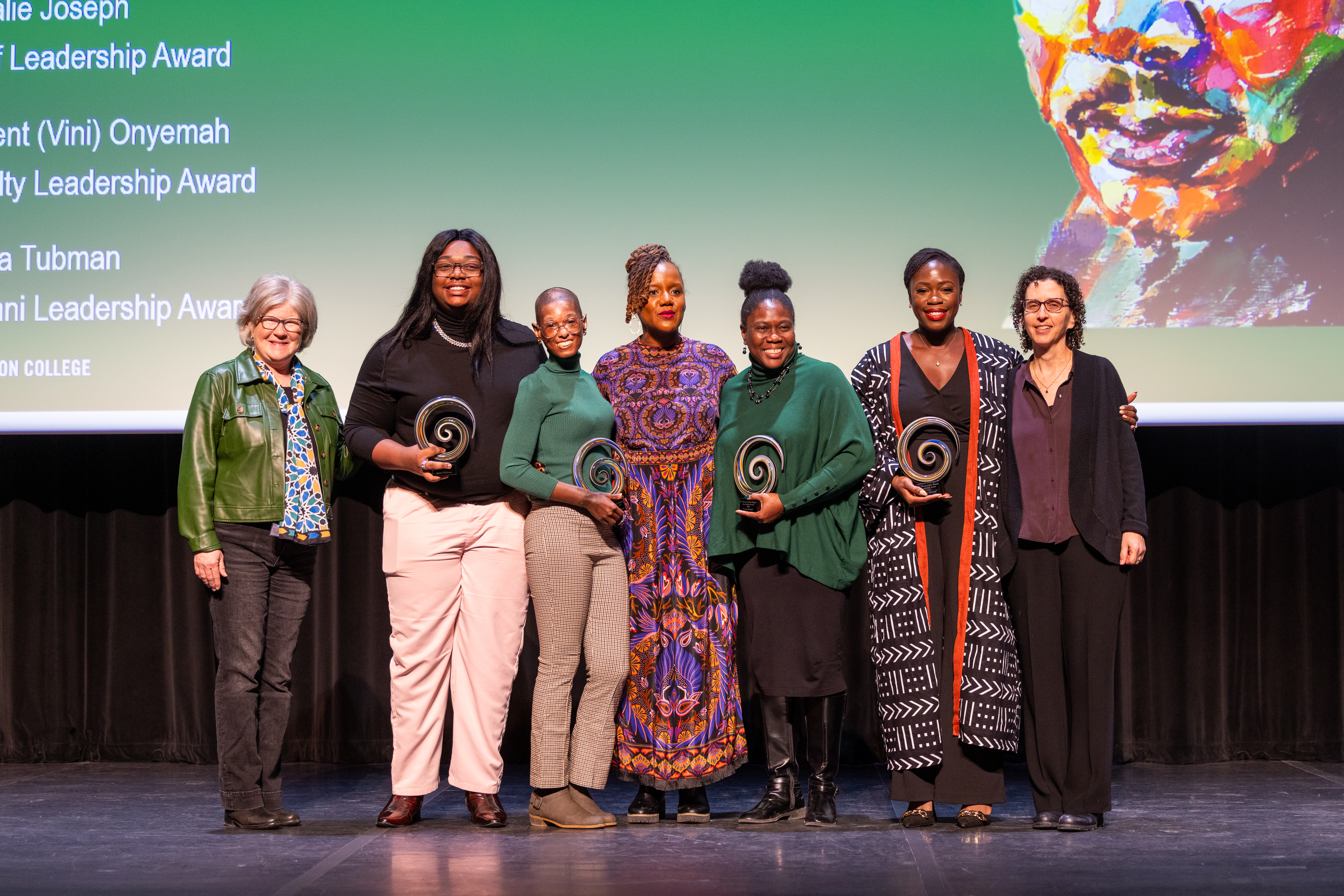 Seven people on a stage holding awards