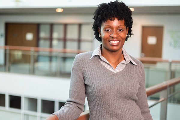 Santucee Bell leans against a balcony railing in Olin Hall at Babson