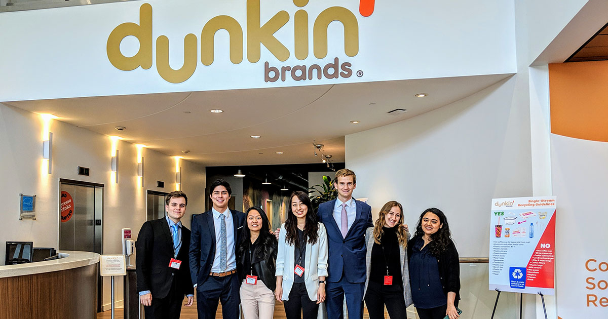 People in front of Dunkin logo