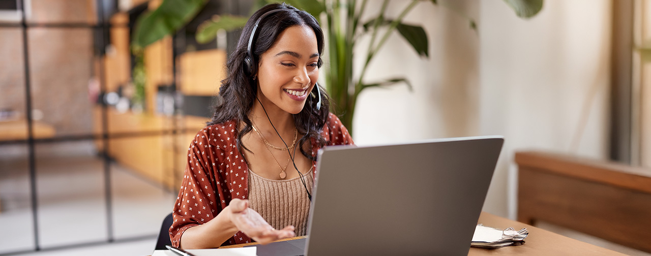 Happy woman with headset at laptop computer