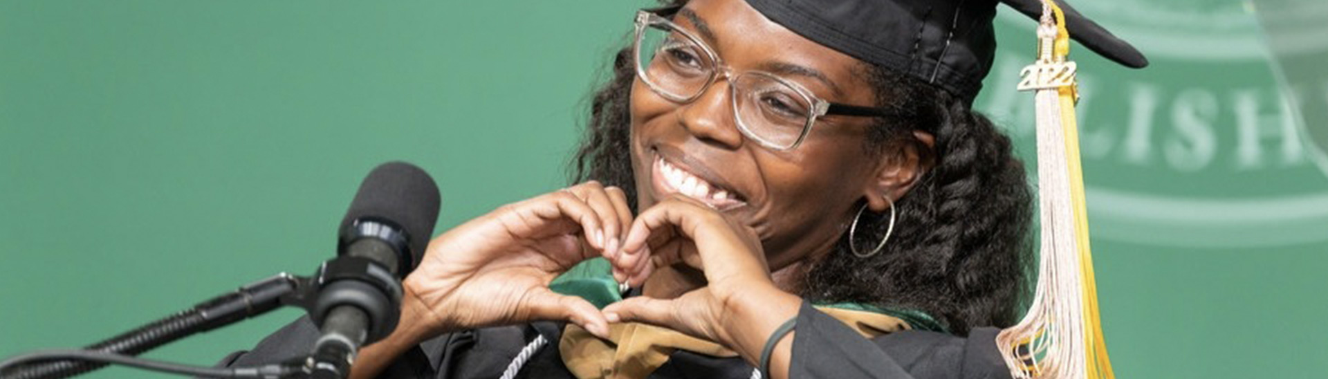graduating student makes a heart shape with hands