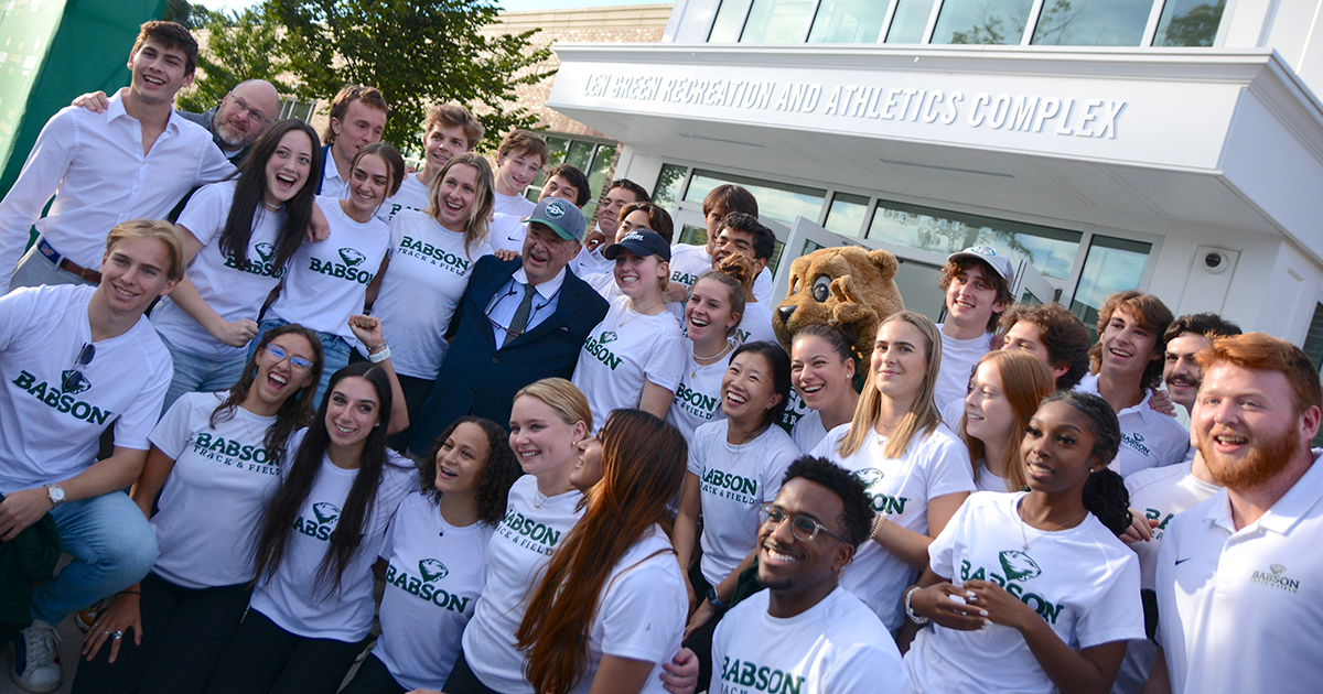 A group of student-athletes pose with Len Green in front of the building named for him
