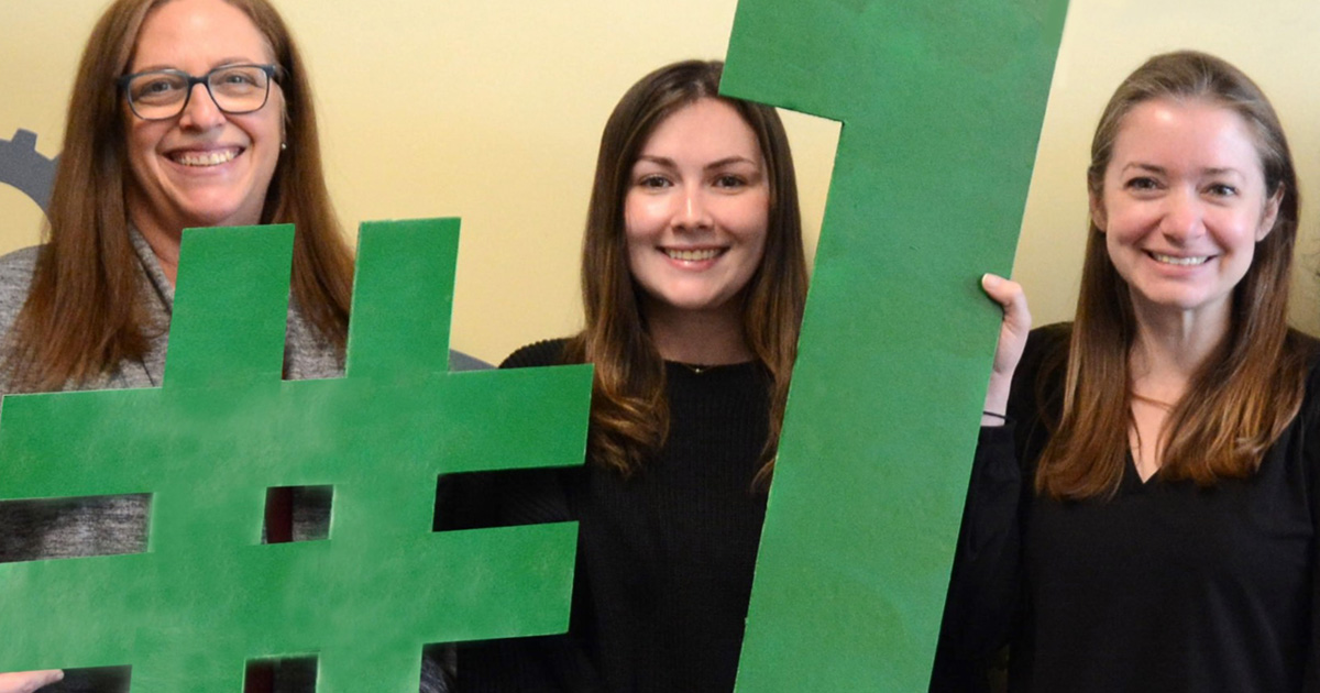 Three people holding #1 sign