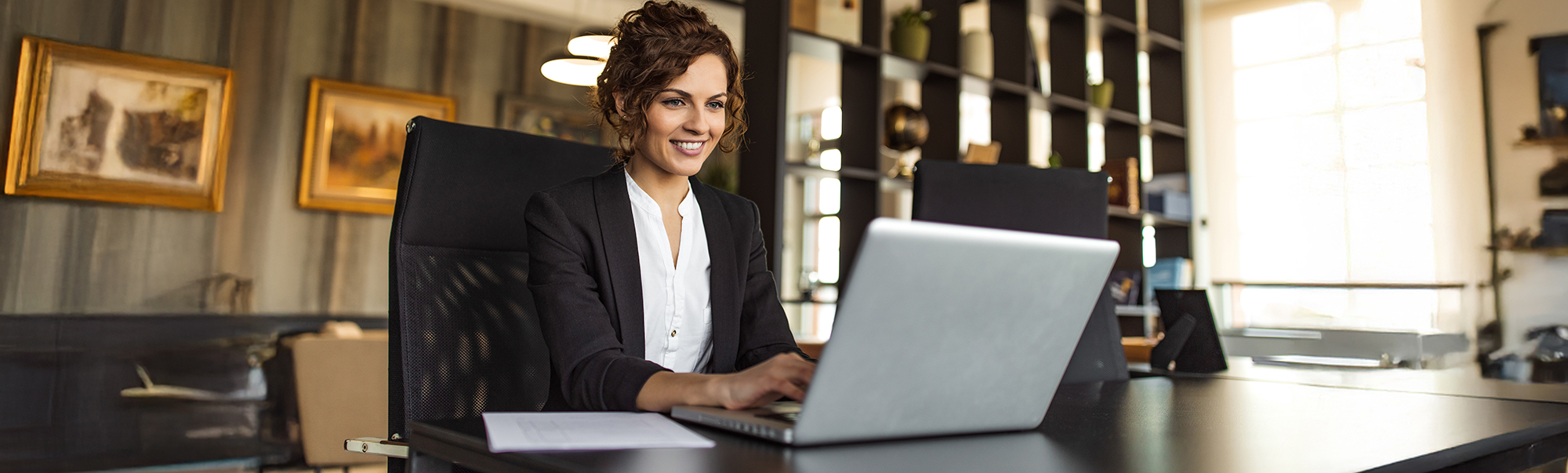 Woman sitting at a desk looking at a laptop