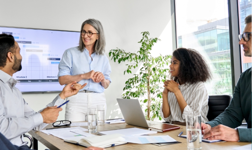 People in a meeting with one person standing a running the meeting