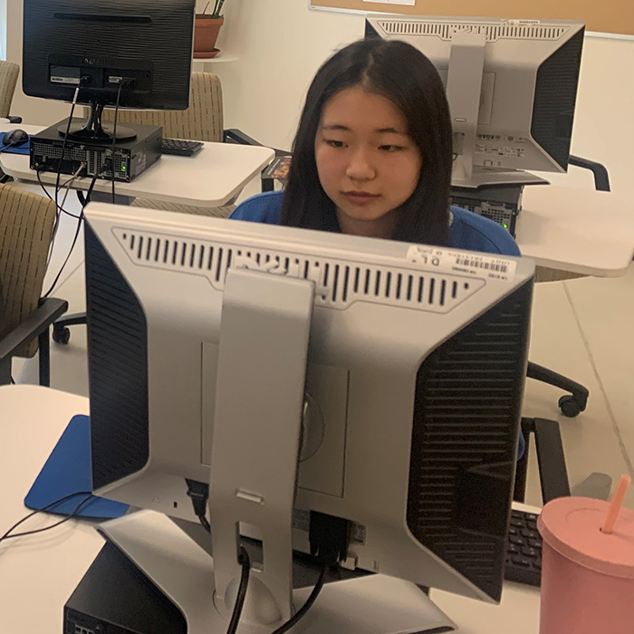 Three students work at computers at a community center.