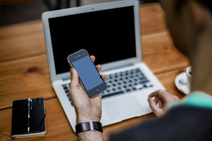 person using mobile phone and laptop